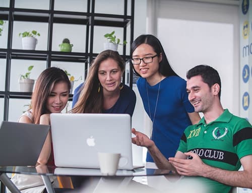 Group of people collaborating around a laptop